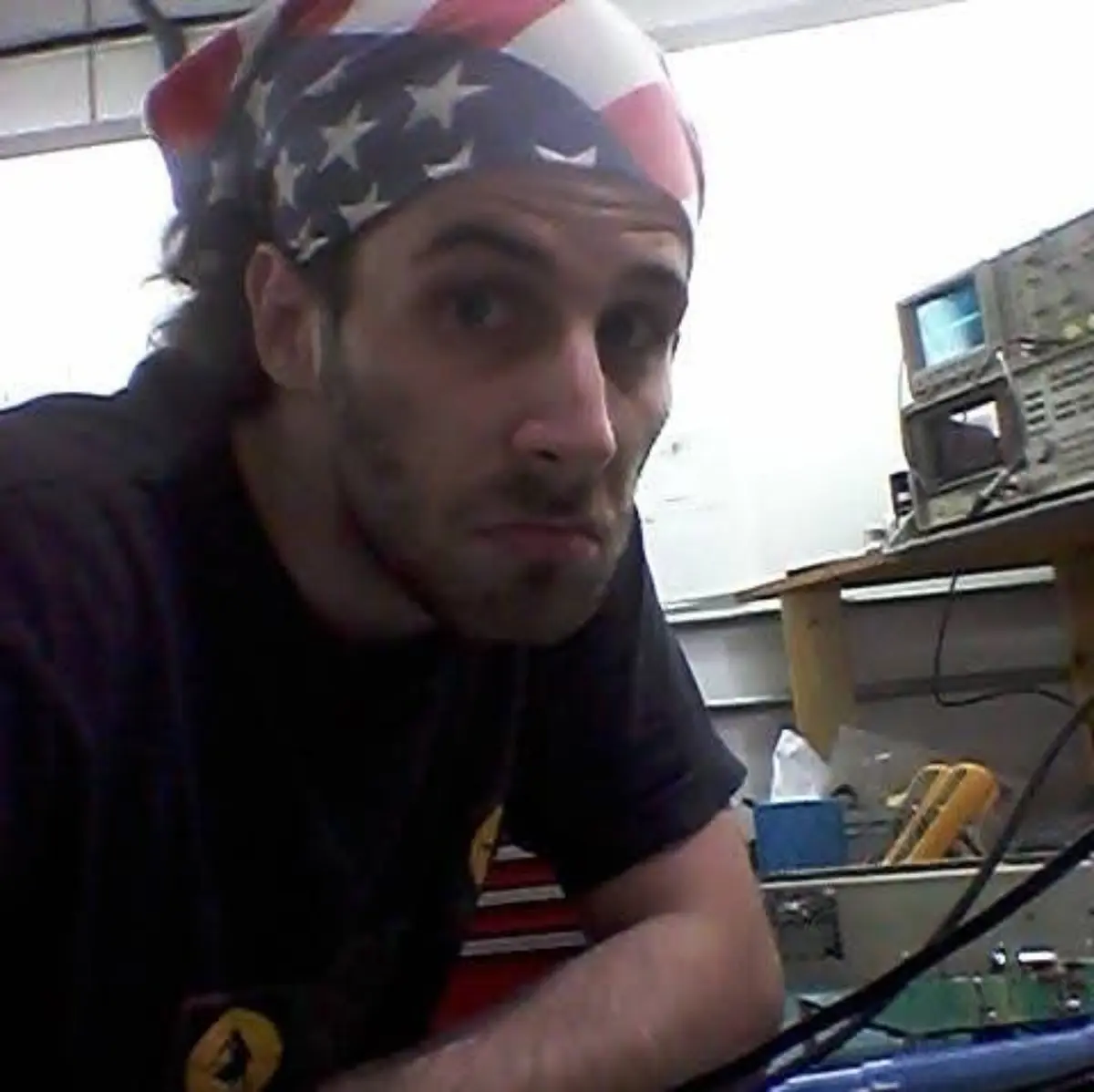 Seth Esquieu leaning over an electronics workbench beside test equipment